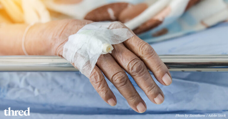 A hand showing signs of age with an IV taped to it.