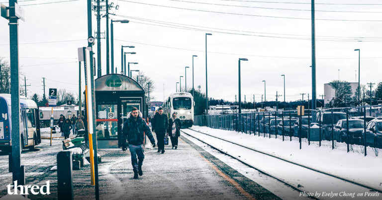 People walking beside a transit line on a snowy day.